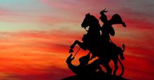 silhouette of George and the Dragon statue, Moscow, in front of a sunset sky